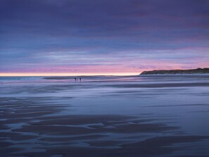 A beach with a calm sea and a sunset sky. - 2 Bed in Bamburgh (oc-nb1969) (Bamburgh)