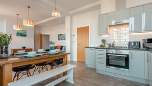 A modern kitchen with a central island, built-in appliances, and pendant lighting. - 2 Bed in Swanage (oc-wy619) (Swanage)