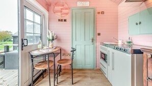 Een keuken met een roze muur, een groene deur en een raam.