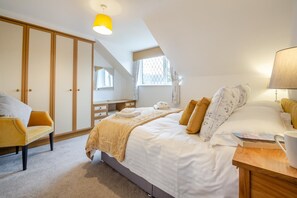 Ein Schlafzimmer mit Bett, Nachttisch, Lampe, Stuhl und Kleiderschrank.