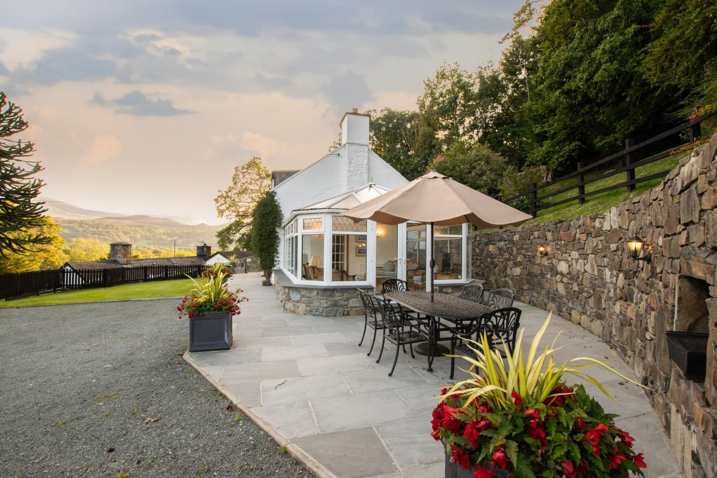 A cozy outdoor patio with a stone wall, a table with chairs, and a large umbrella.