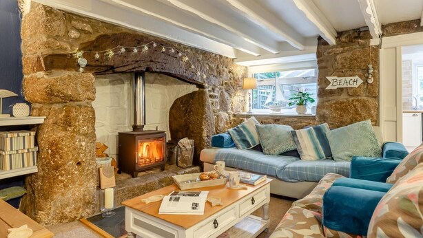 Una sala de estar acogedora con chimenea de piedra, un sofá y una mesa de centro.