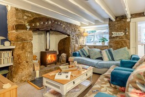 A cozy living room with a stone fireplace, a sofa, and a coffee table. - 2 Bed in St. Ives (oc-g33644) (Halsetown)