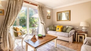 A cozy living room with a sofa, a wooden coffee table, and a dining table. There are curtains, a lamp, and a mirror on the wall. - 2 Bed in Hickling (oc-1794) (Hickling)