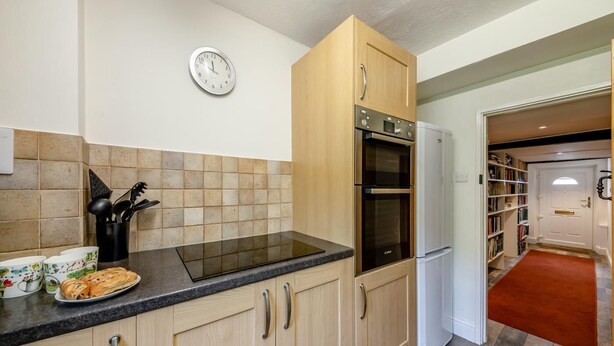 A kitchen with wooden cabinets, a black countertop, a stainless steel oven, and a white refrigerator. - 2 Bed in Pooley Bridge (oc-r33740) (Pooley Bridge)