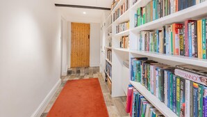 A hallway with a wooden door, a red carpet, and white bookshelves filled with books. - 2 Bed in Pooley Bridge (oc-r33740) (Pooley Bridge)