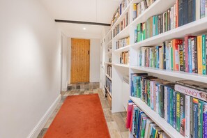 Ein Flur mit einer Holztür, einem roten Teppich und weißen Bücherregalen voller Bücher.