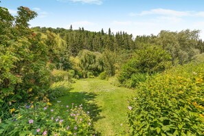 A lush garden with a variety of plants and flowers, a clear sky, and a bench in the center. - 2 Bed in Pooley Bridge (oc-r33740) (Pooley Bridge)