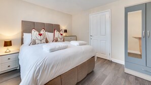 Ein modernes Schlafzimmer mit einem großen Bett, Nachttischen, einem Kleiderschrank und einer Kandelaber.