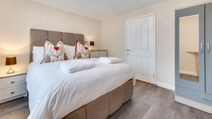 Een moderne slaapkamer met een groot bed, nachtkastjes, een garderobe en een kroonluchter.