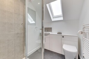 A modern bathroom with a glass shower enclosure, a skylight, a white sink, and a toilet. - 2 Bed in Great Waldingfield (oc-ac3) (Great Waldingfield)