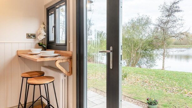 Keittiössä on puinen työtaso, valkoinen pesuallas ja ikkuna, josta avautuu näkymä järvelle.