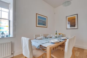 A dining area with a table set for four, chairs, a window with blinds, and two framed pictures on the wall. - 2 Bed in Embleton (oc-nb1960) (Embleton)