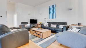 Ett modernt vardagsrum med en soffgrupp, ett soffbord och en tv.
