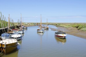 Uma correnteza tranquila com vários barcos atracados na margem, ladeada por margens gramadas.