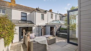 A courtyard with a seating area, a shop, and a glass door leading to a garden. - 3 Bed in Padstow (oc-f33036) (Padstow)