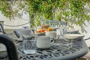 A table set with a teapot, cups, a glass, and a plate with food and a bottle of orange juice. - 3 Bed in Padstow (oc-f33036) (Padstow)