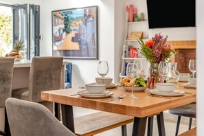 A dining area with a wooden table set for two, including plates, bowls, and glasses. - 3 Bed in Padstow (oc-f33036) (Padstow)