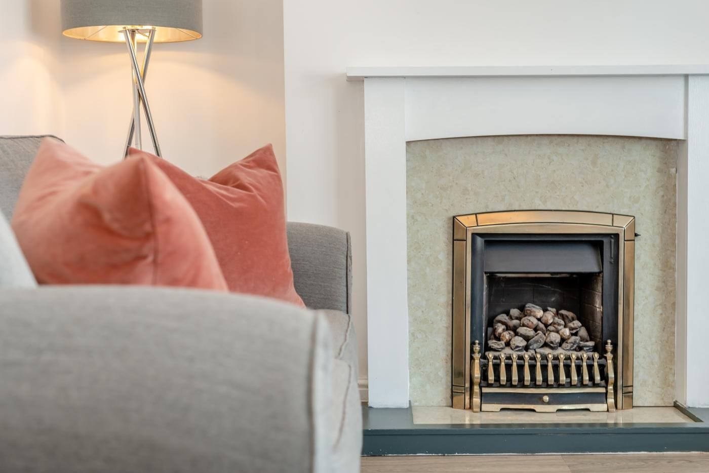 A living room with a fireplace, a grey sofa, and a floor lamp.
