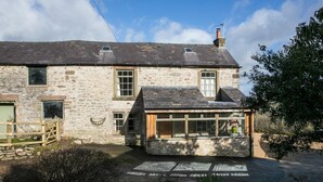 A stone house with a sloped roof, a wooden porch, and a small garden area.