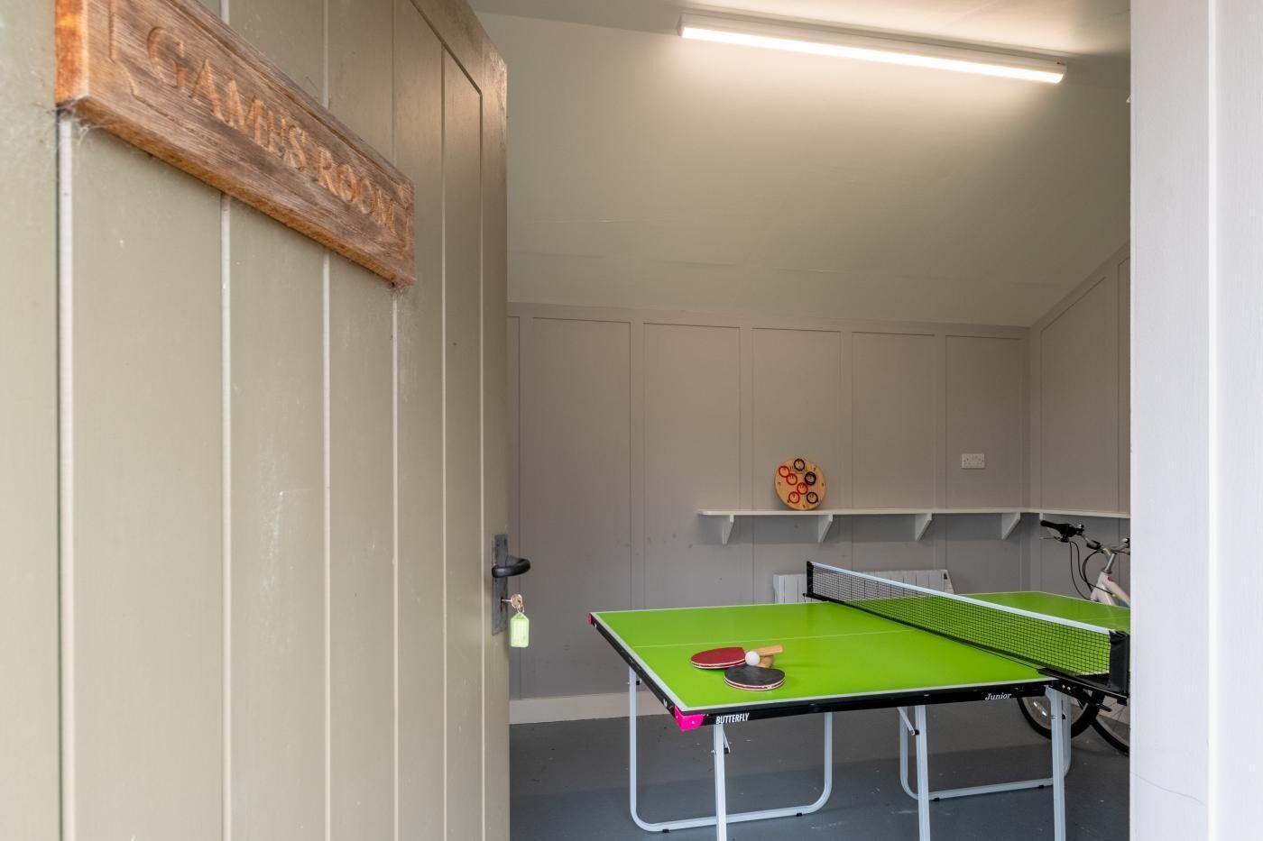 Een tafeltennistafel in een kamer met een deur waarop 