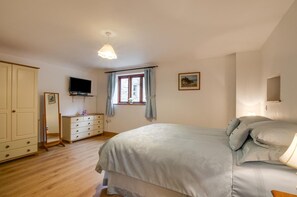 A bedroom with a bed, a dresser, a television, a window with curtains, and a painting on the wall. - 2 Bed in Machynlleth (oc-491245) (Llanwrin)