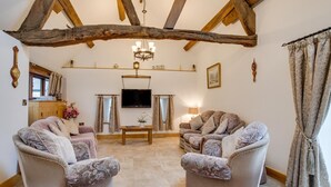 Un salon chaleureux avec deux fauteuils à motifs, une table basse en bois et un téléviseur.