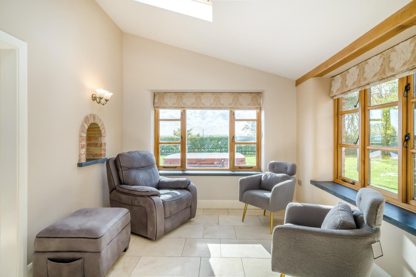 Una habitación con un ventanal grande, chimenea y un área de estar con sillón de masaje y reposapiés.