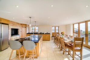 A modern kitchen with a central island, wooden cabinets, and a dining area with a large window.