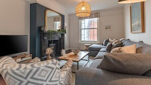 A living room with a TV, sofa, and fireplace. - 2 Bed in Southwold (oc-brec) (Southwold)