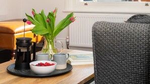 A cozy room with a wooden table, a black coffee maker, a bowl of berries, and a vase with green leaves. - 2 Bed in Southwold (oc-brec) (Southwold)