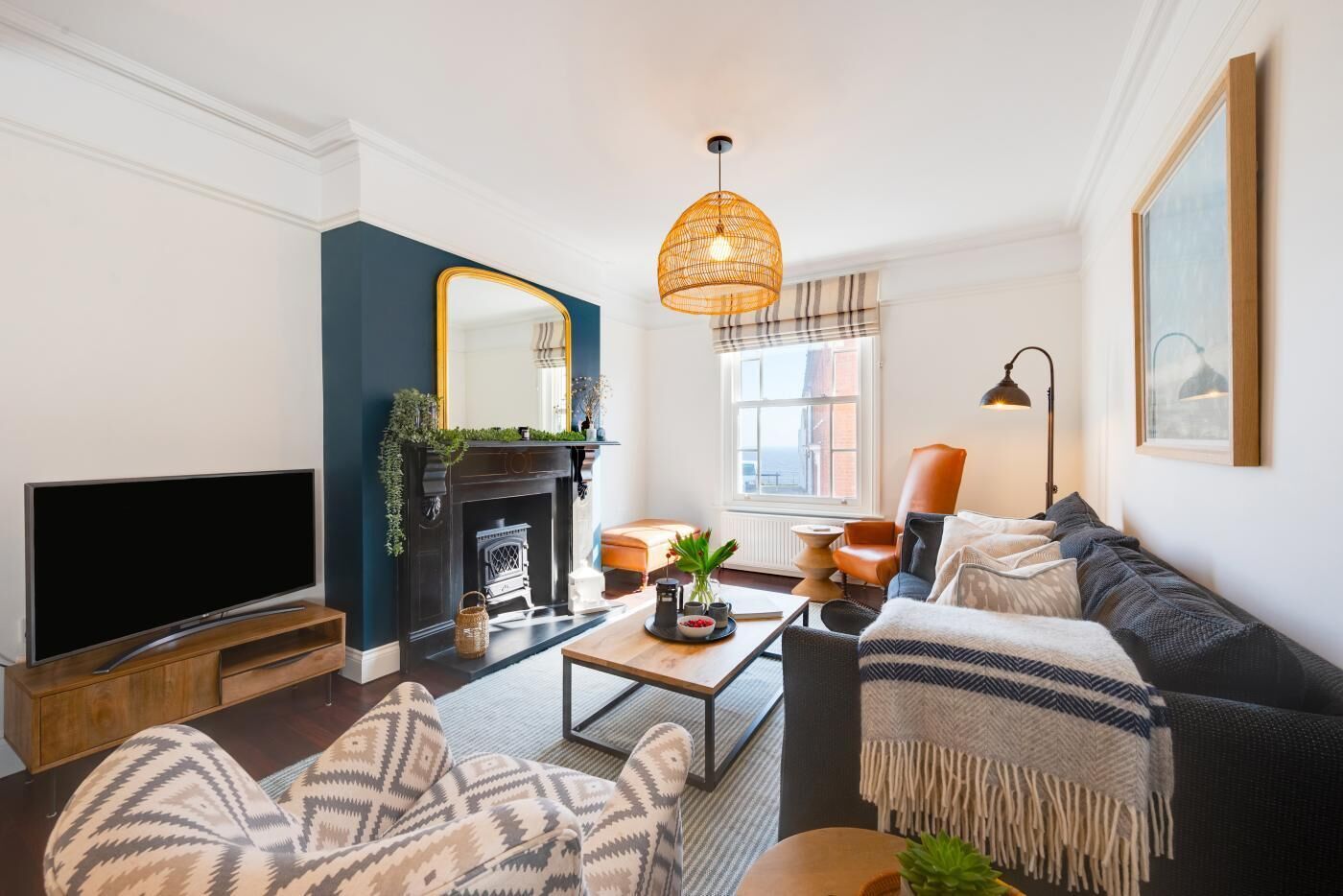 A living room with a fireplace, sofa, television, and a hanging light fixture.