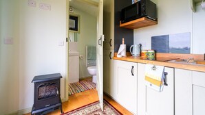 Pieni ja käytännöllinen keittiö, jossa on puuliesi, mikroaaltouuni ja pieni pesuallas.
