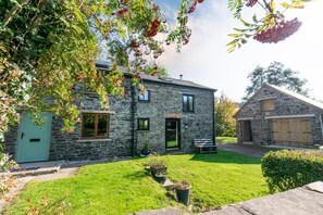 A stone house with a green door, a small front porch, and a well-maintained lawn. - 2 Bed in Brecon (oc-37318) (Pentre-bach)