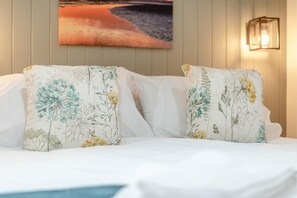 A bed with floral-patterned pillows and a wall-mounted light fixture.