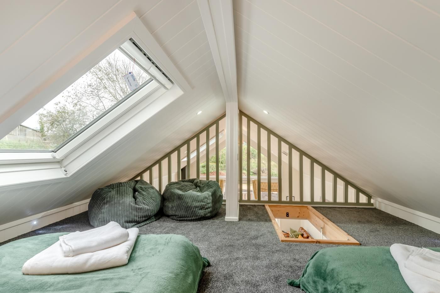 A room with a sloped ceiling, a skylight, and a wooden loft bed.