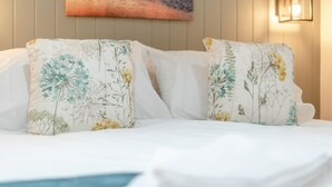 A bed with white linens and two decorative pillows with floral patterns. - 2 Bed in Mouswald (oc-b33444) (Mouswald)
