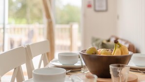 A dining table with a bowl of fruit, white plates, and cups. - 2 Bed in Mouswald (oc-b33444) (Mouswald)