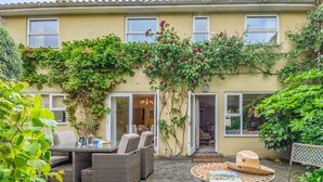 Una casa con un patio arredato con mobili in vimini, un tavolo con una rivista e un cappello.