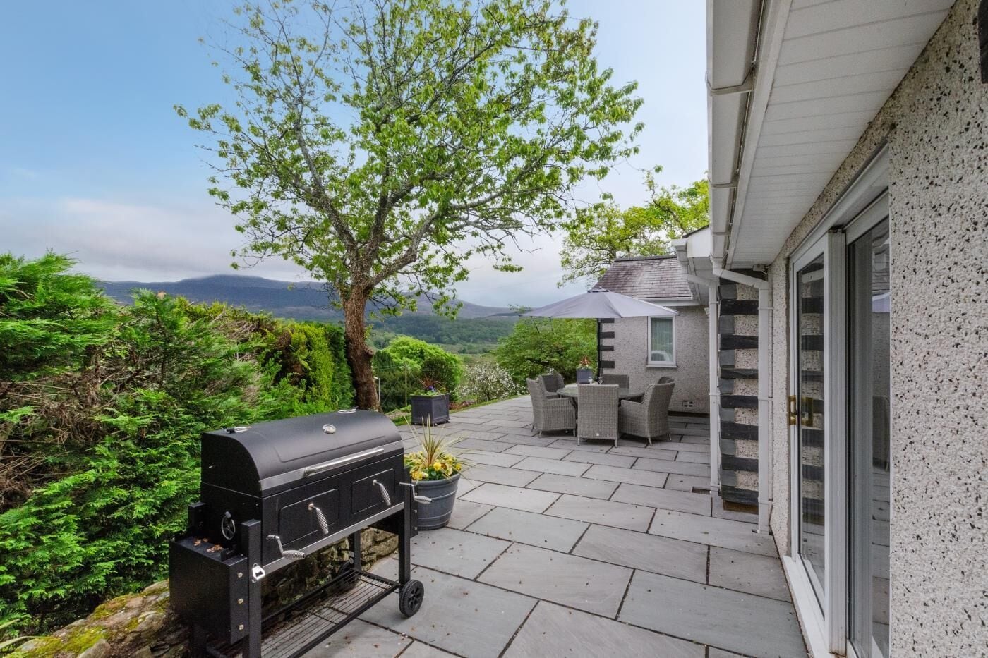 Une terrasse avec un barbecue, du mobilier d’extérieur et une vue sur le paysage.