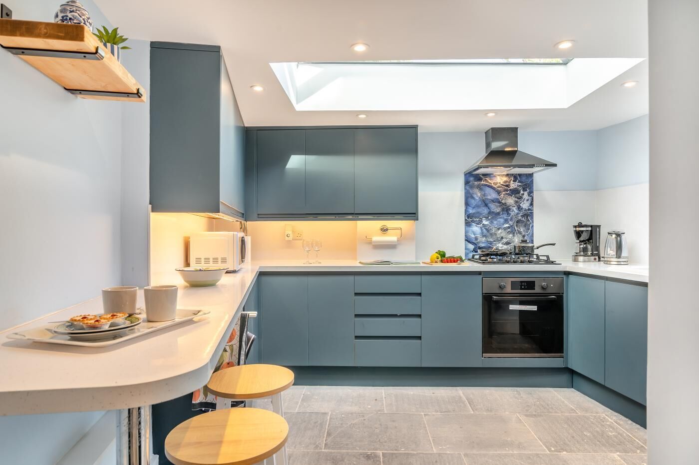 A modern kitchen with a skylight, built-in appliances, and a bar area.