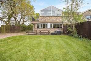 Une maison en pierre dotée d’un grand patio, d’un espace couvert et d’une clôture en bois.