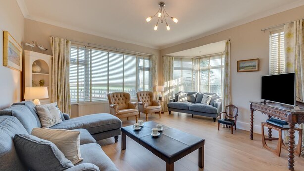 A spacious living room with a large sofa, two armchairs, a coffee table, and a television. - 4 Bed in Old Hunstanton (oc-1809) (Hunstanton)