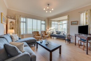 A spacious living room with a large sofa, two armchairs, a coffee table, and a television. - 4 Bed in Old Hunstanton (oc-1809) (Hunstanton)