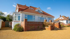 A two-story house with a brick facade, a covered porch, and a gravel driveway. - 4 Bed in Old Hunstanton (oc-1809) (Hunstanton)