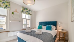 A bedroom with a large bed, a bedside table, a window with a view, and a wall-mounted light fixture. - 2 Bed in Bath (oc-bhr44) (Bath)