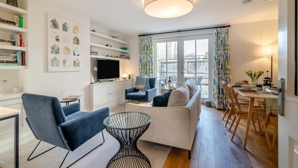 A modern living room with a sofa, armchairs, a TV, and a dining area with a table and chairs. - 2 Bed in Bath (oc-bhr44) (Bath)