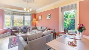A spacious living room with a large window, a dining table, and a fireplace. - 3 Bed in Bakewell (oc-r33436) (Bakewell)