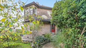 A stone building with a red door, surrounded by lush greenery and a stone pathway. - 3 Bed in Bakewell (oc-r33436) (Bakewell)