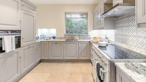 A modern kitchen with light grey cabinets, a built-in oven, a large stove, and a window with blinds. - 3 Bed in Bakewell (oc-r33436) (Bakewell)